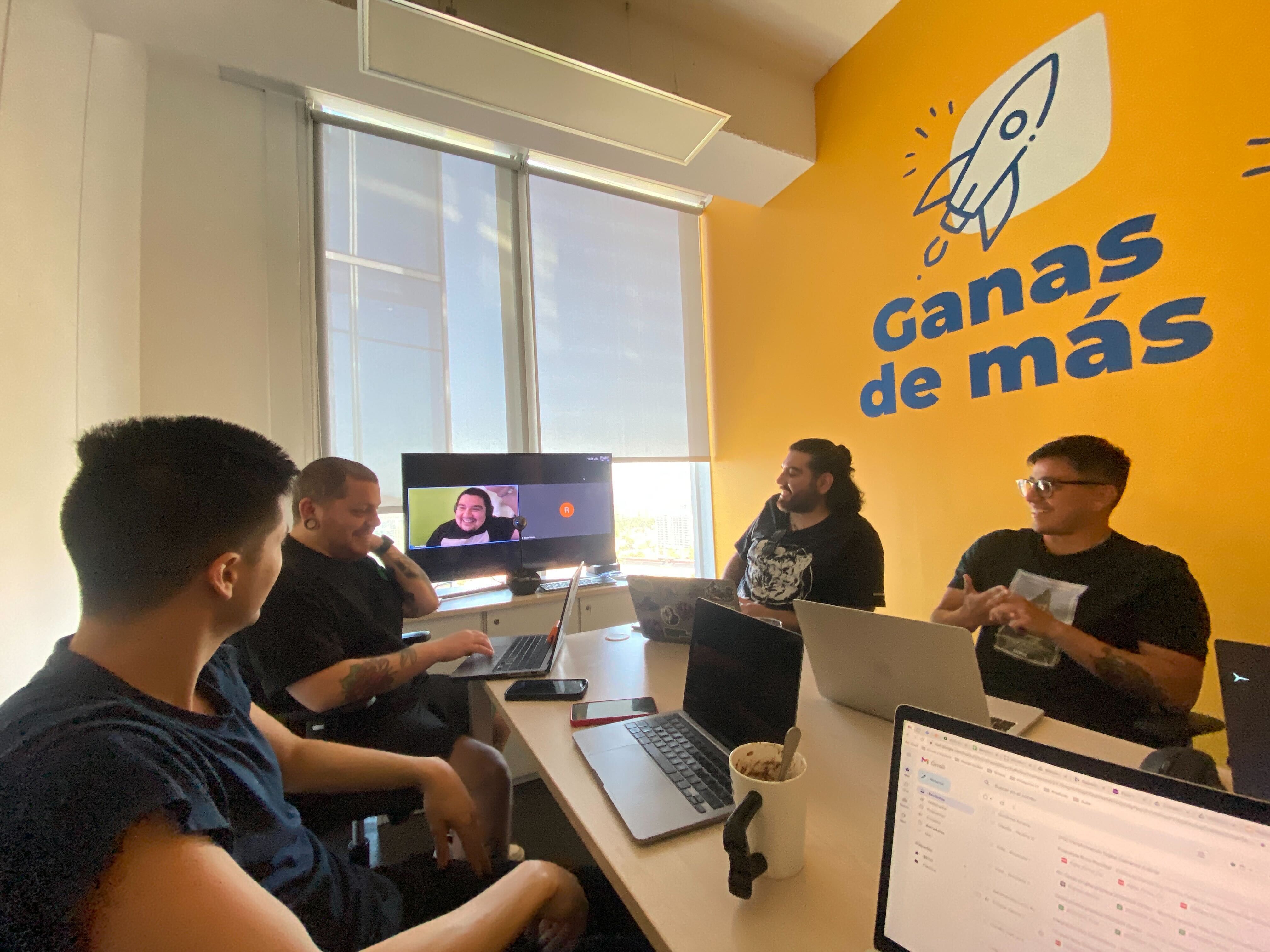Reunión de equipo bajo el mural Ganas de más